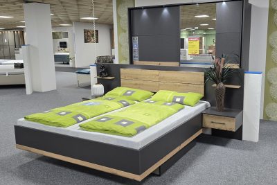 Schlafzimmer Boston in grau metallic Dekor mit Absetzung Eiche Artisan. Bestehend aus: Bettanlage mit Nako ( Außenmaß  B 279 x T 207 cm) Bett 180 x 200 cm, Schwebetürenschrank 2türig mit 1 Spiegel und Passepartourahmen mit Beleuchtung und Türendämpfer. Rollbettkastenpaar unter dem Bett.