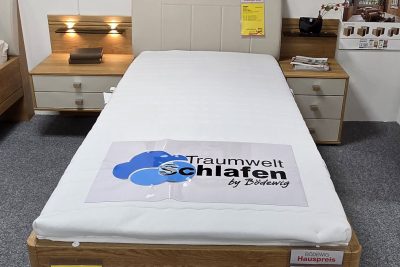 Komfortbett 90 x 190 cm schwebend in Eiche teilmassiv. Kopfteil Stoff in Lederoptik beige. Inklusive 2 Nachtkommoden 1 x 40 cm breit stehend, 1 x 60 cm breit schwebend. Ohne Lattenrost, Matratzen und Deko.