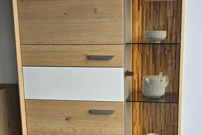 Vitrine in Eiche massiv, satin gebeizt mit Absetzung in Lack weiß. 2 Holztüren, 1 Glastür, 1 Schubkasten. Inklusive LED-Sockel- und Glasbeleuchtung. Maß B 102 x H 184 x T 41 cm. Ohne Deko